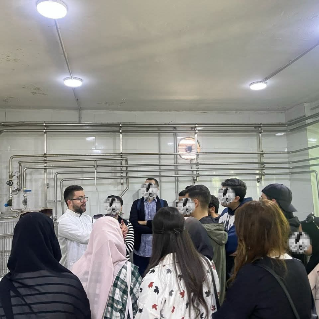 Process-area group briefing — Discussing production stages alongside the stainless-steel process piping.